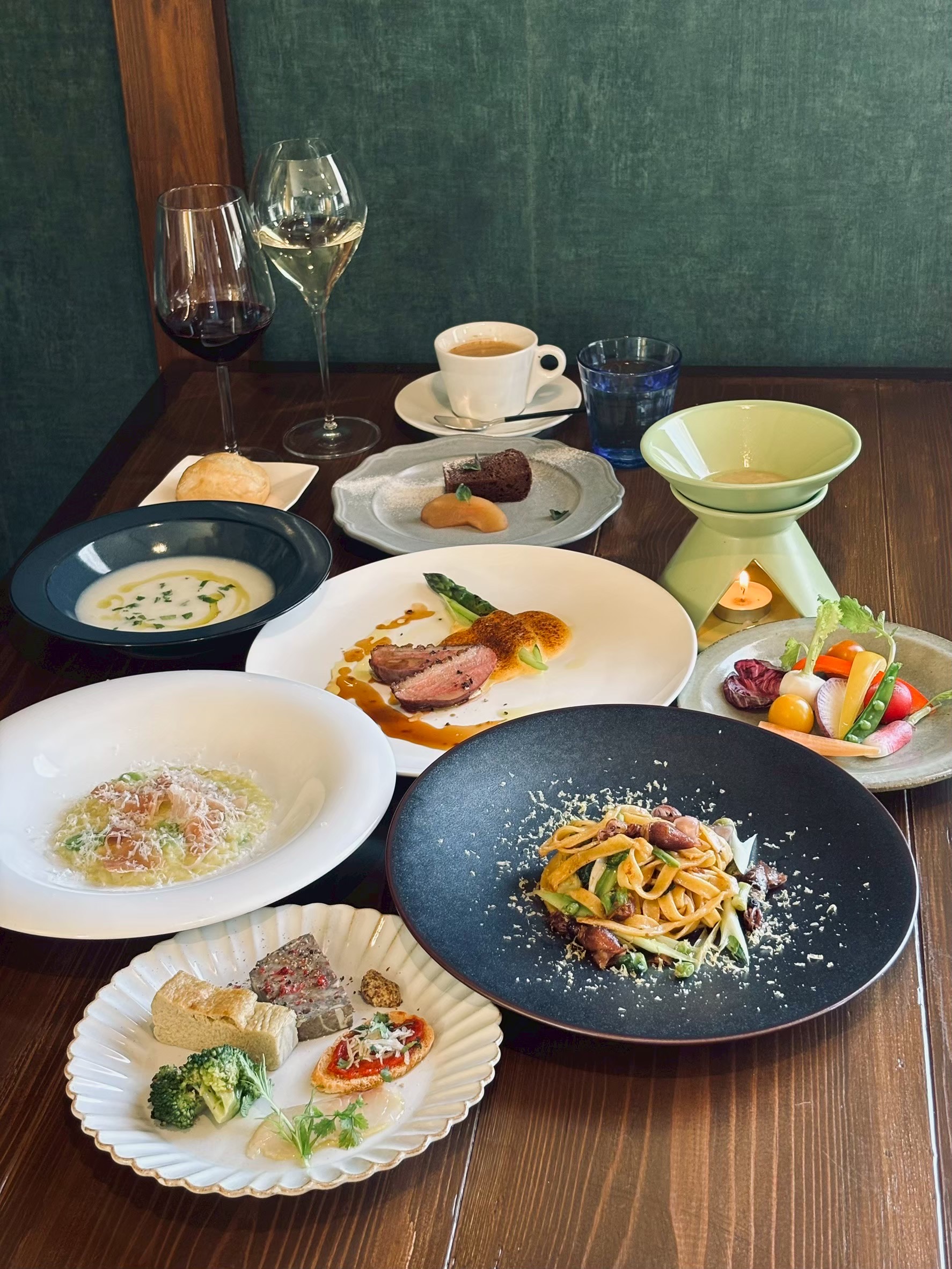 パスタ、肉料理、前菜とワインが並ぶテーブル